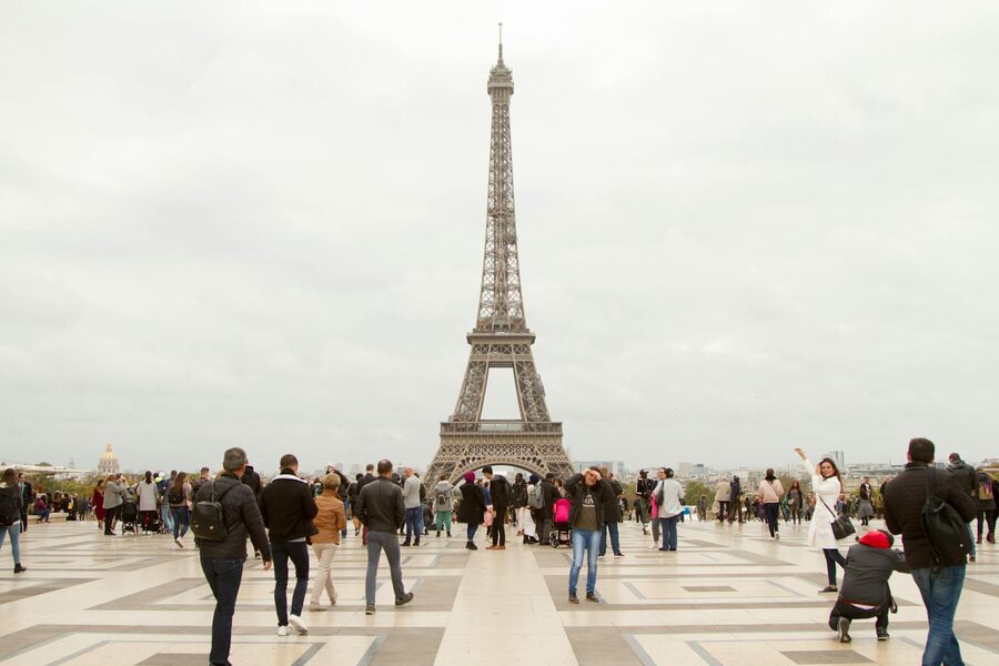 The Eiffel Tower towering above a Paris street with pedestrians walking beneath it
