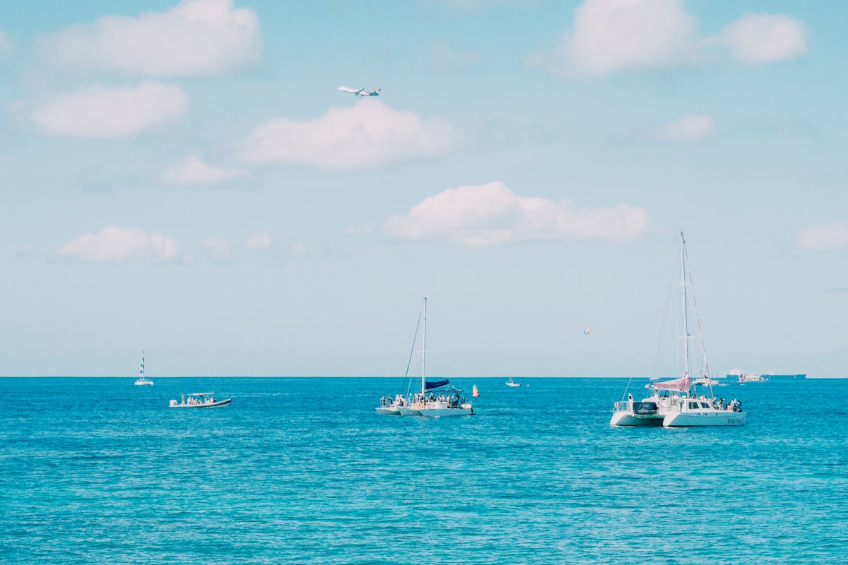 Aerial shot of a catamaran sailing with passengers on a clear blue sea