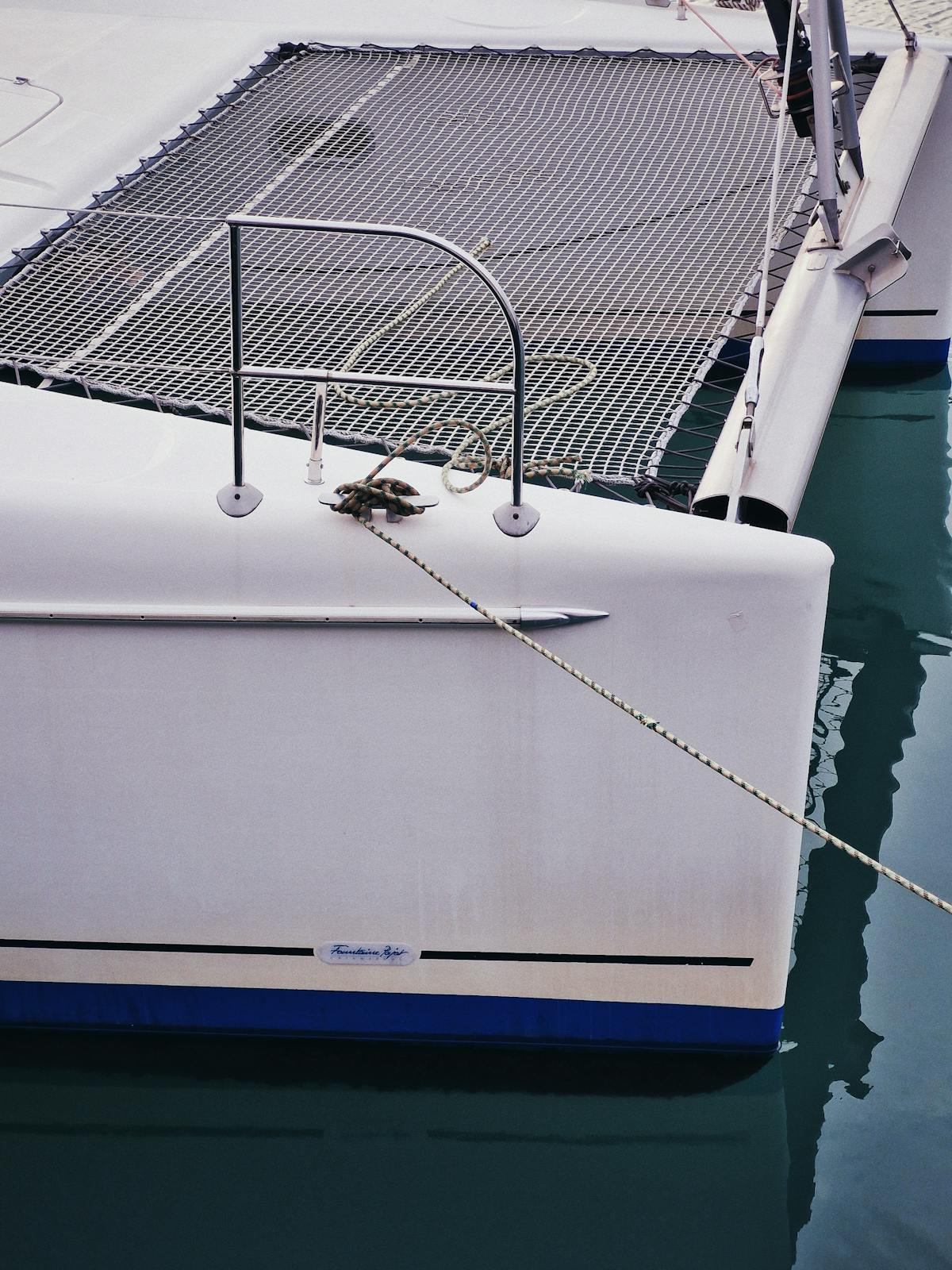 Catamaran bow with marine ropes floating in a tranquil marina