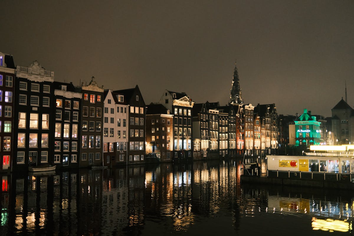 Amsterdam canal houses illuminated at night with reflections
