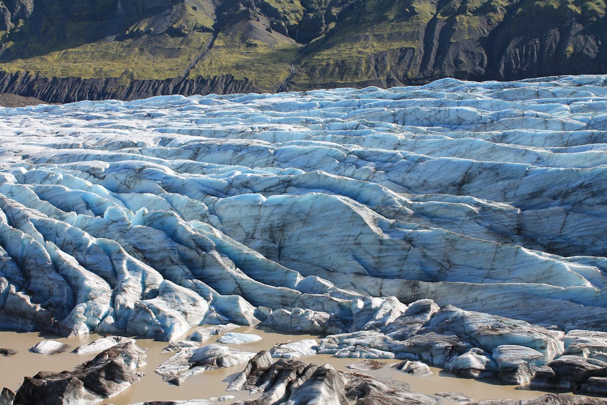 Blue glacier face with rugged mountain terrain in Iceland