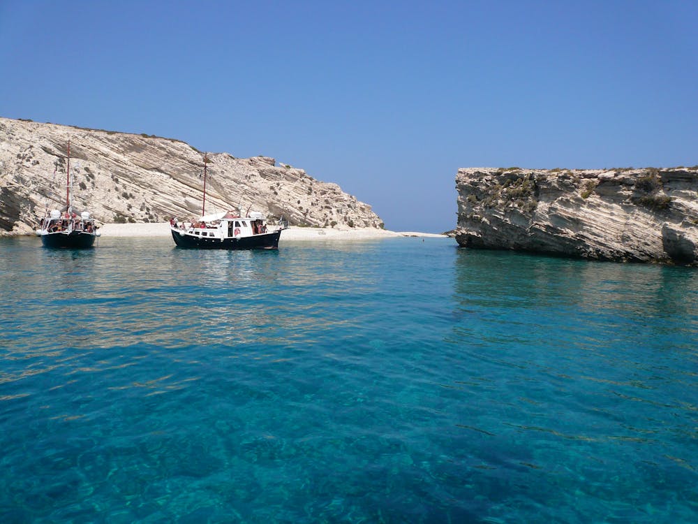 Colourful boats on crystal clear blue water near Greek island