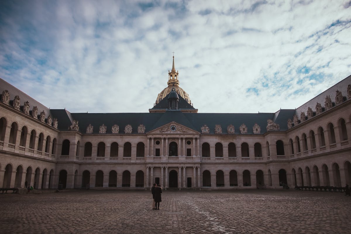 The inner courtyard of Les Invalides with the chapel dome visible under cloudy winter sky