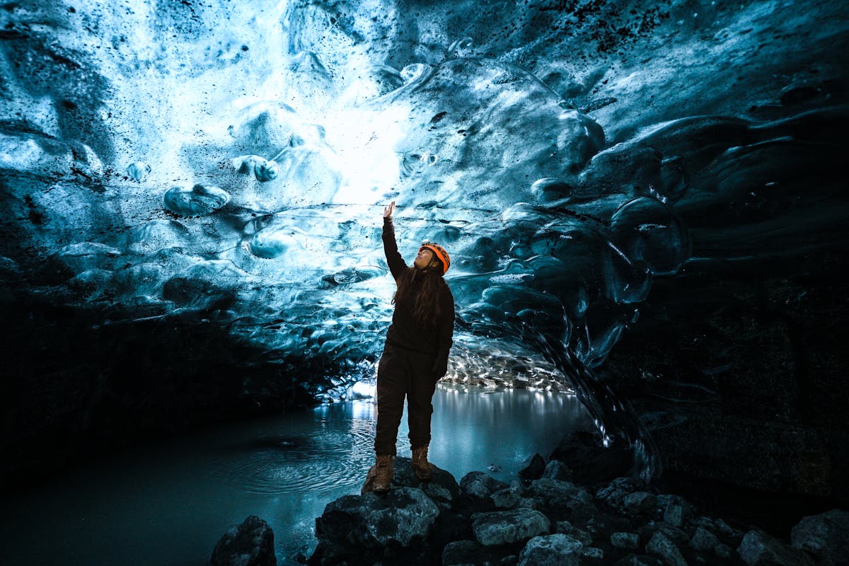 Person exploring vivid blue ice cave in Iceland wearing hiking gear