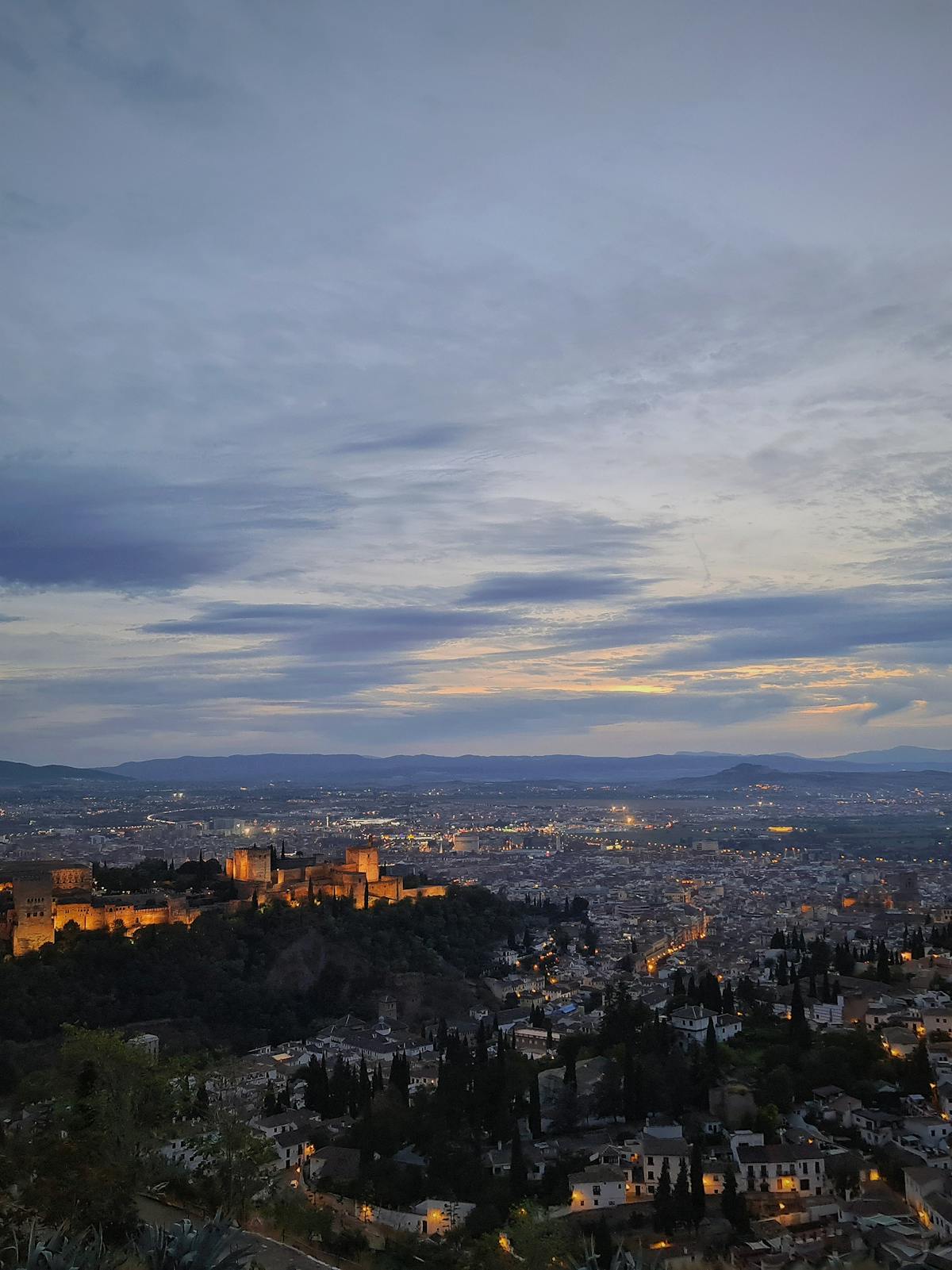 Alhambra palace illuminated at dusk seen from a Granada viewpoint