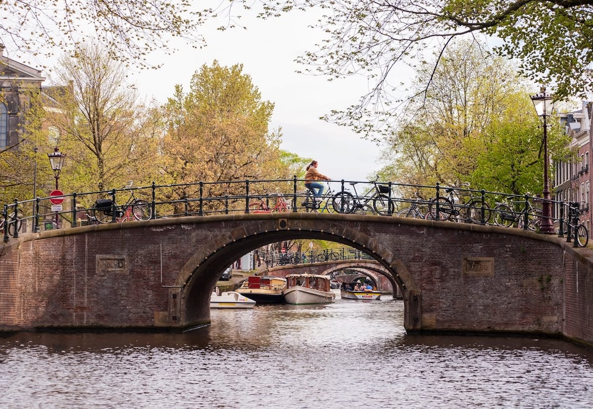 Amsterdam canal in autumn with orange leaves on trees and bicycles on the bridge
