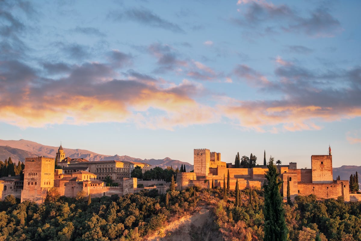 The Alhambra palace lit by sunrise seen from the Albaicin neighborhood in Granada