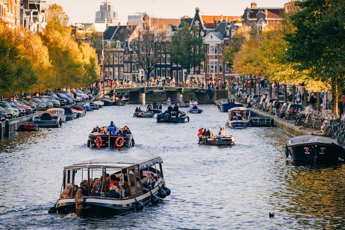 Tour boat cruising through an Amsterdam canal beneath a stone bridge