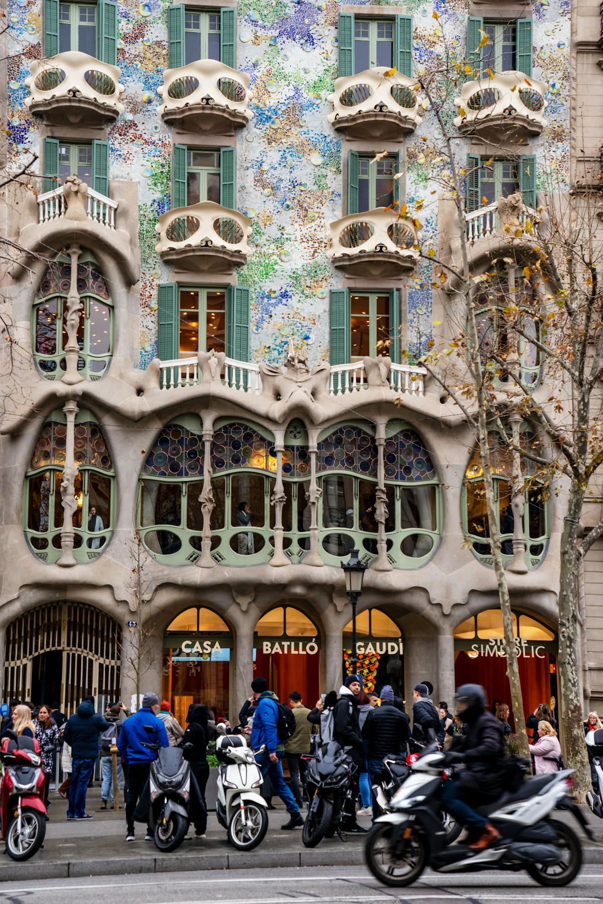 Ornate Casa Batllo facade with people walking on the street in Barcelona Spain