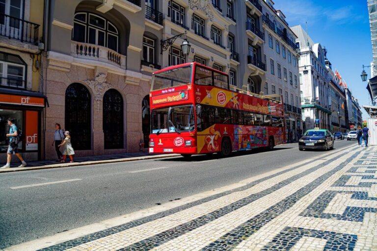 A colorful sightseeing tour bus driving through a street in Lisbon