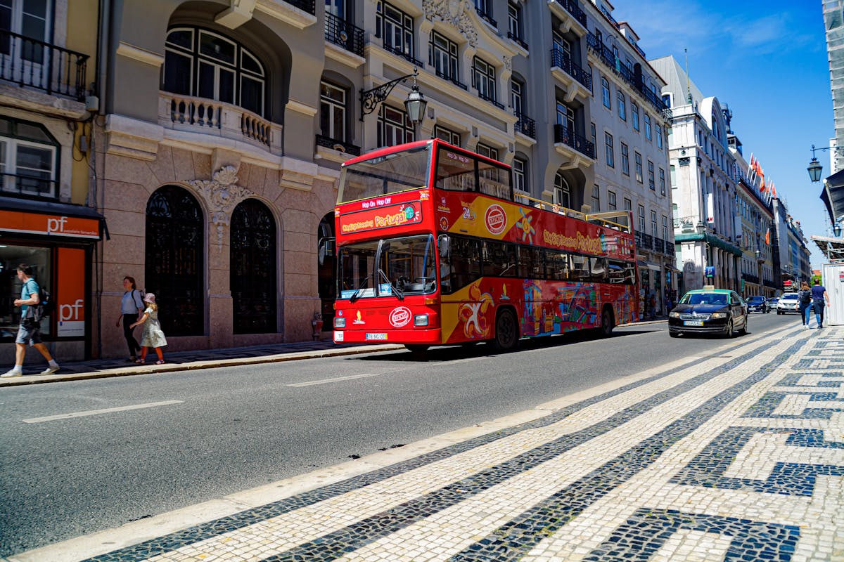 A colorful sightseeing tour bus driving through a street in Lisbon