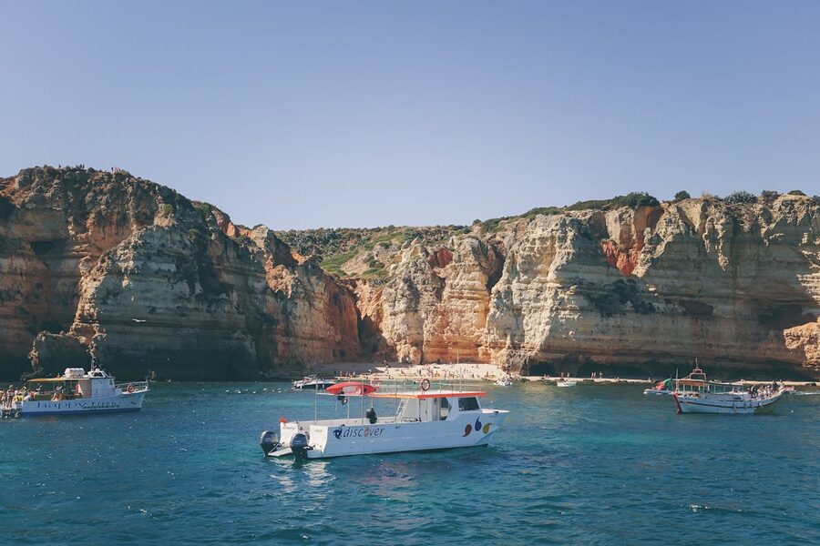 Rocky cliffs tower above clear blue waters during a boat tour in the Algarve