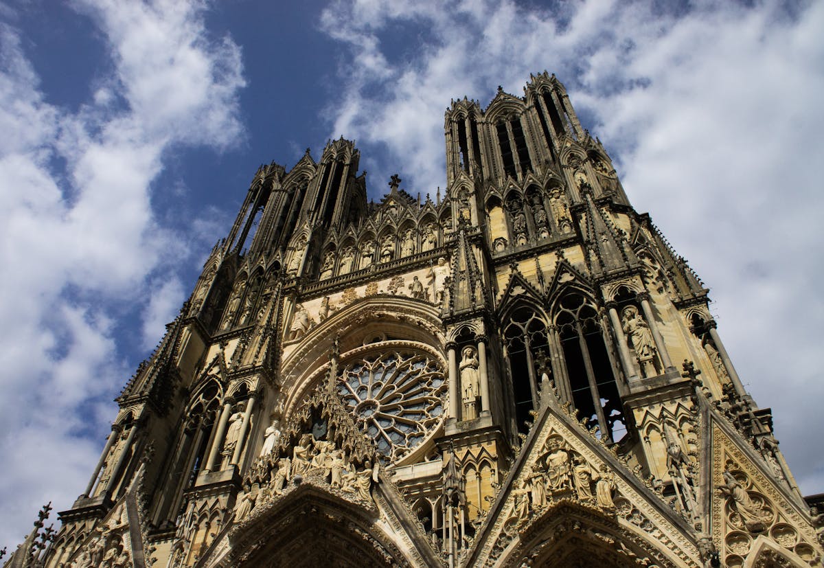 The towering Gothic architecture of Notre-Dame de Reims Cathedral against a blue sky