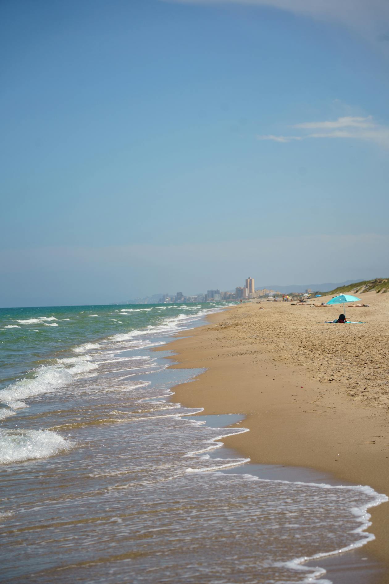 Valencia beach with gentle waves and the city skyline in the distance