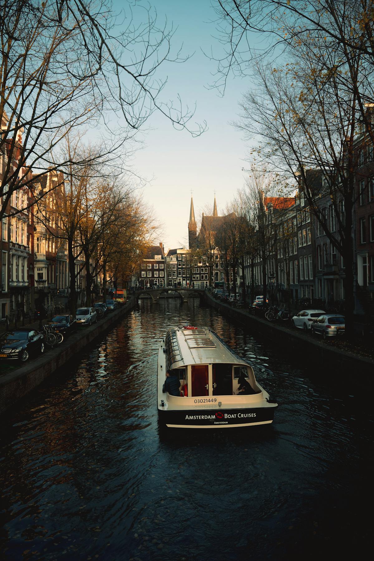 Small boats lining a sunny Amsterdam canal with historic buildings