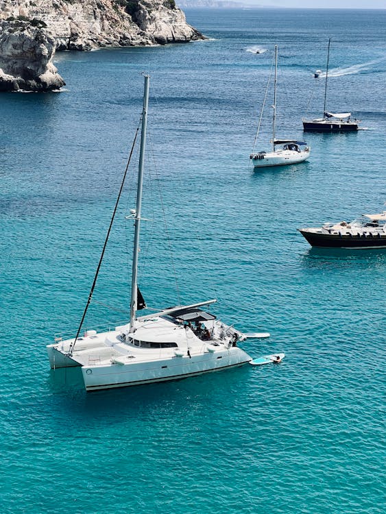 Yacht sailing in turquoise waters near rocky cliffs