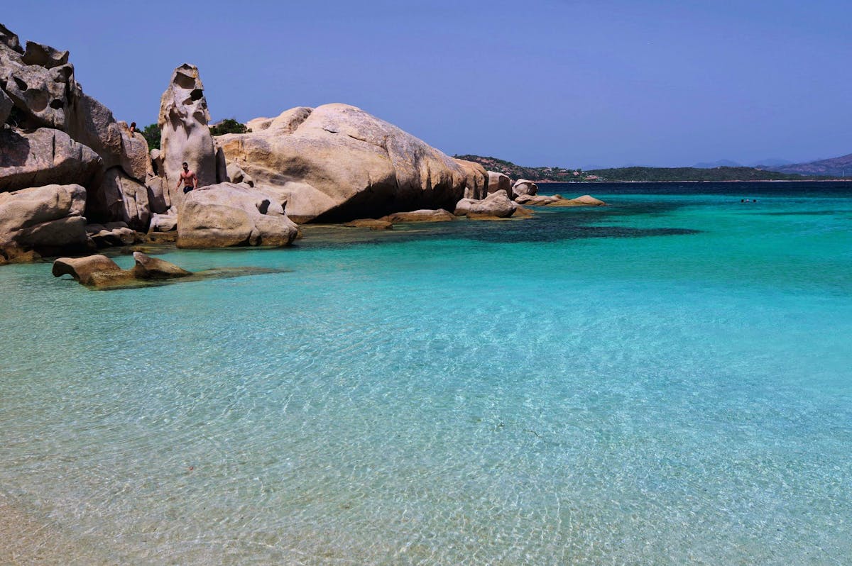 Turquoise beach with unique rock formations under sunny skies in Sardinia