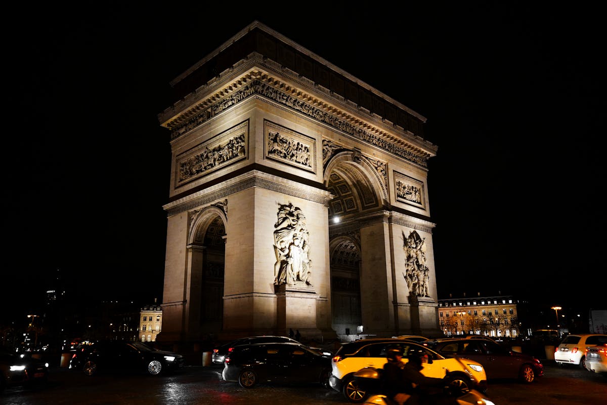 The Arc de Triomphe lit up at night with streaks of traffic flowing around it