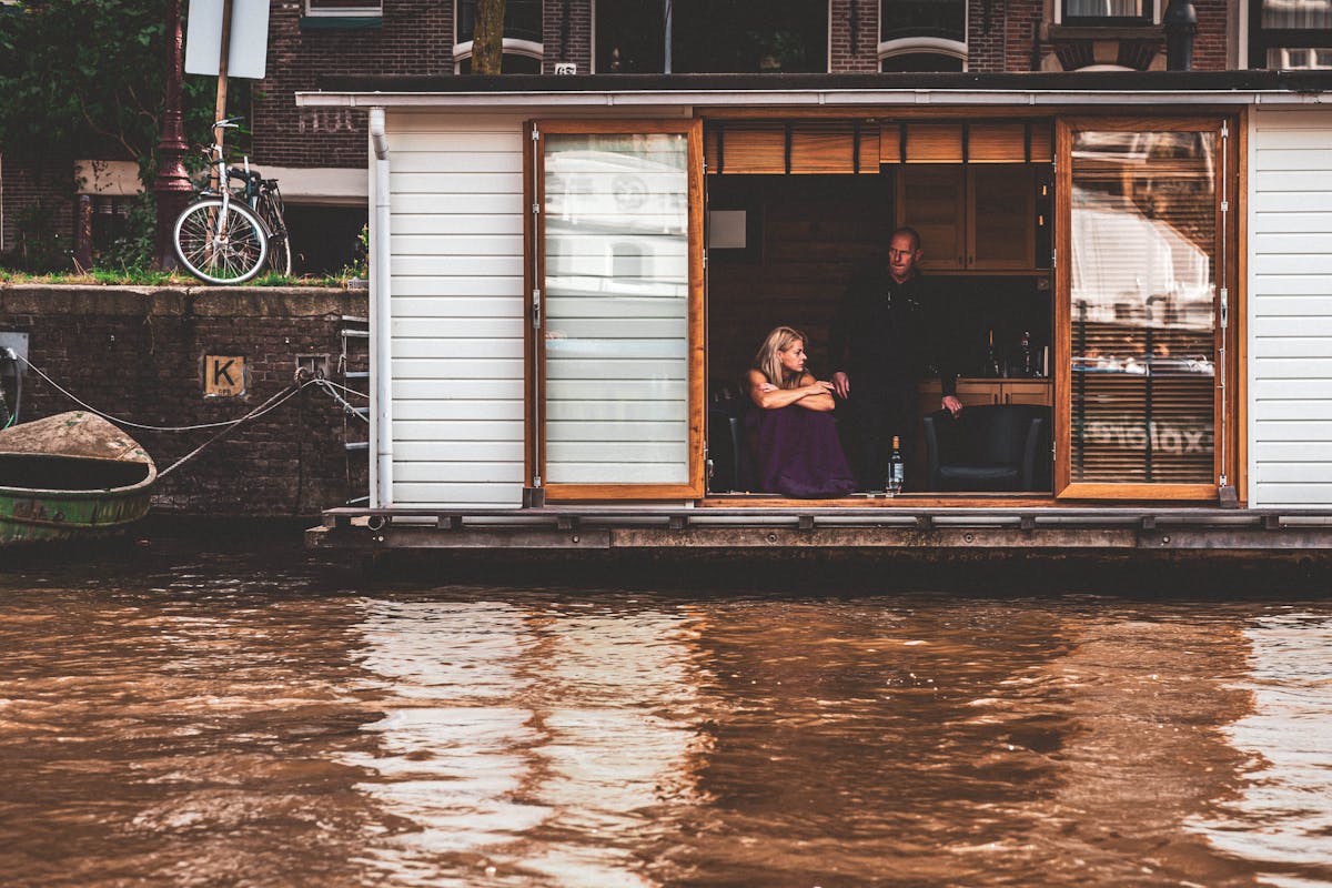 Traditional houseboat moored along a tree-lined Amsterdam canal