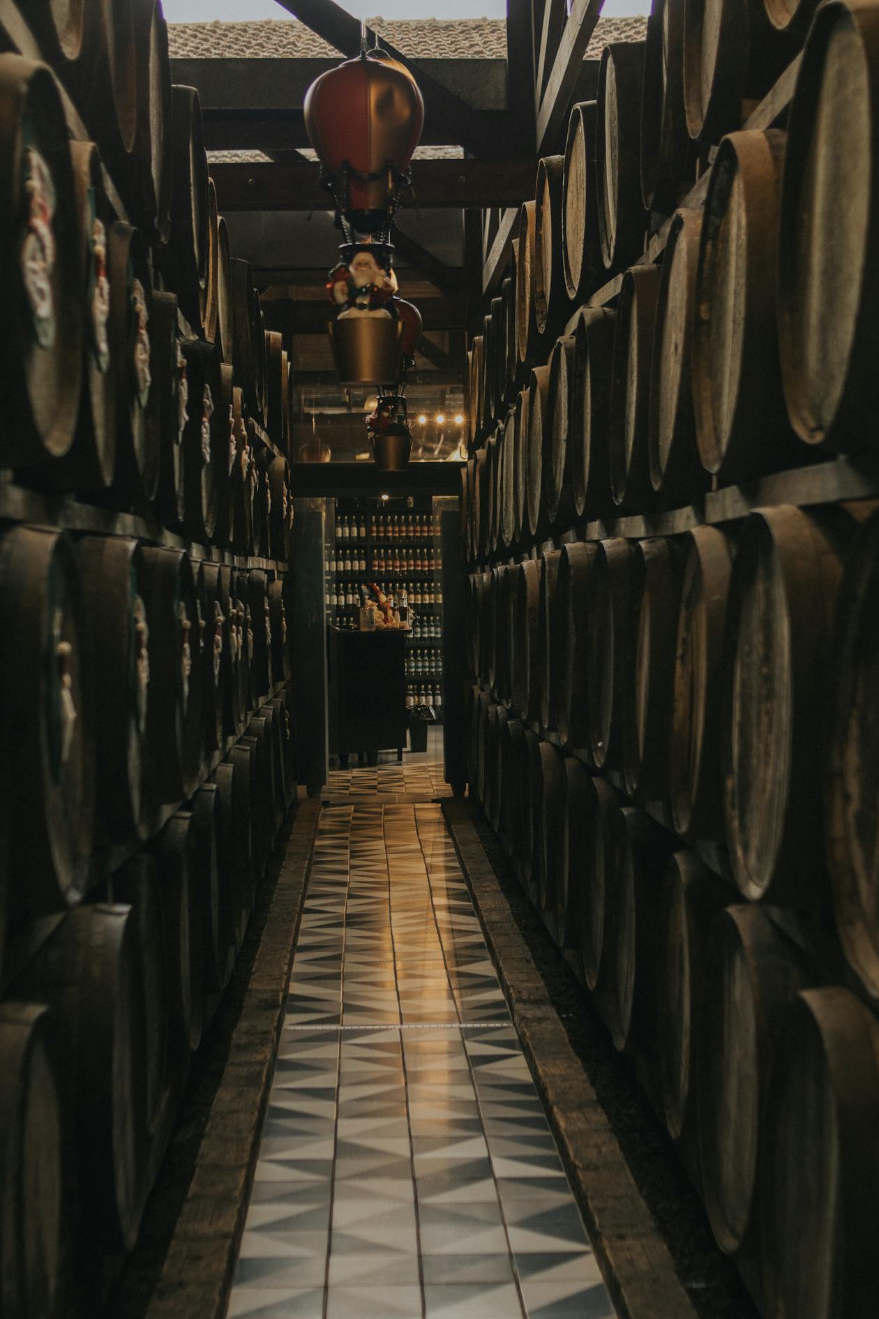 Dimly lit wine cellar with rows of aged oak barrels