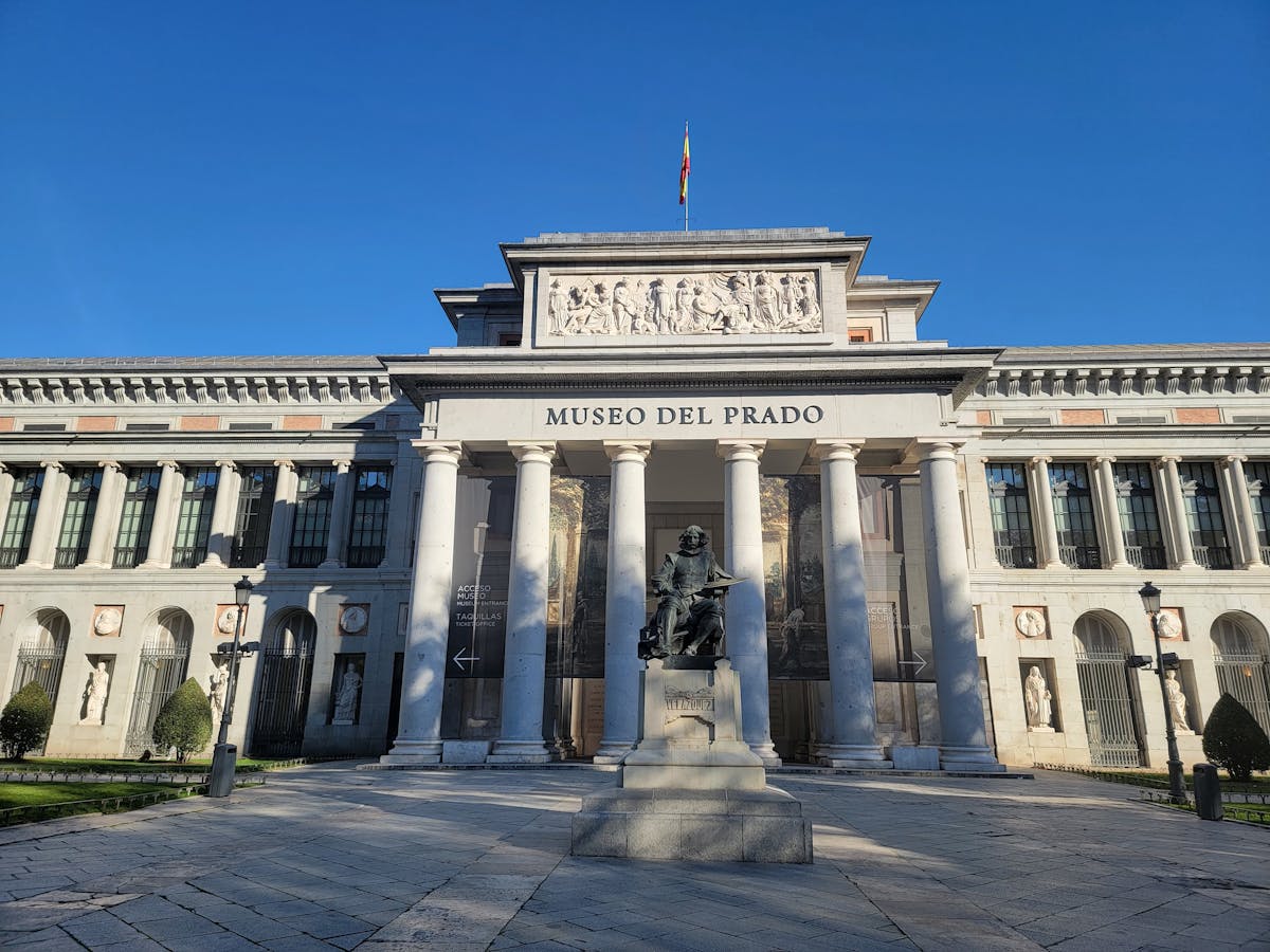 The Prado Museum neoclassical facade under clear blue skies in Madrid, Spain