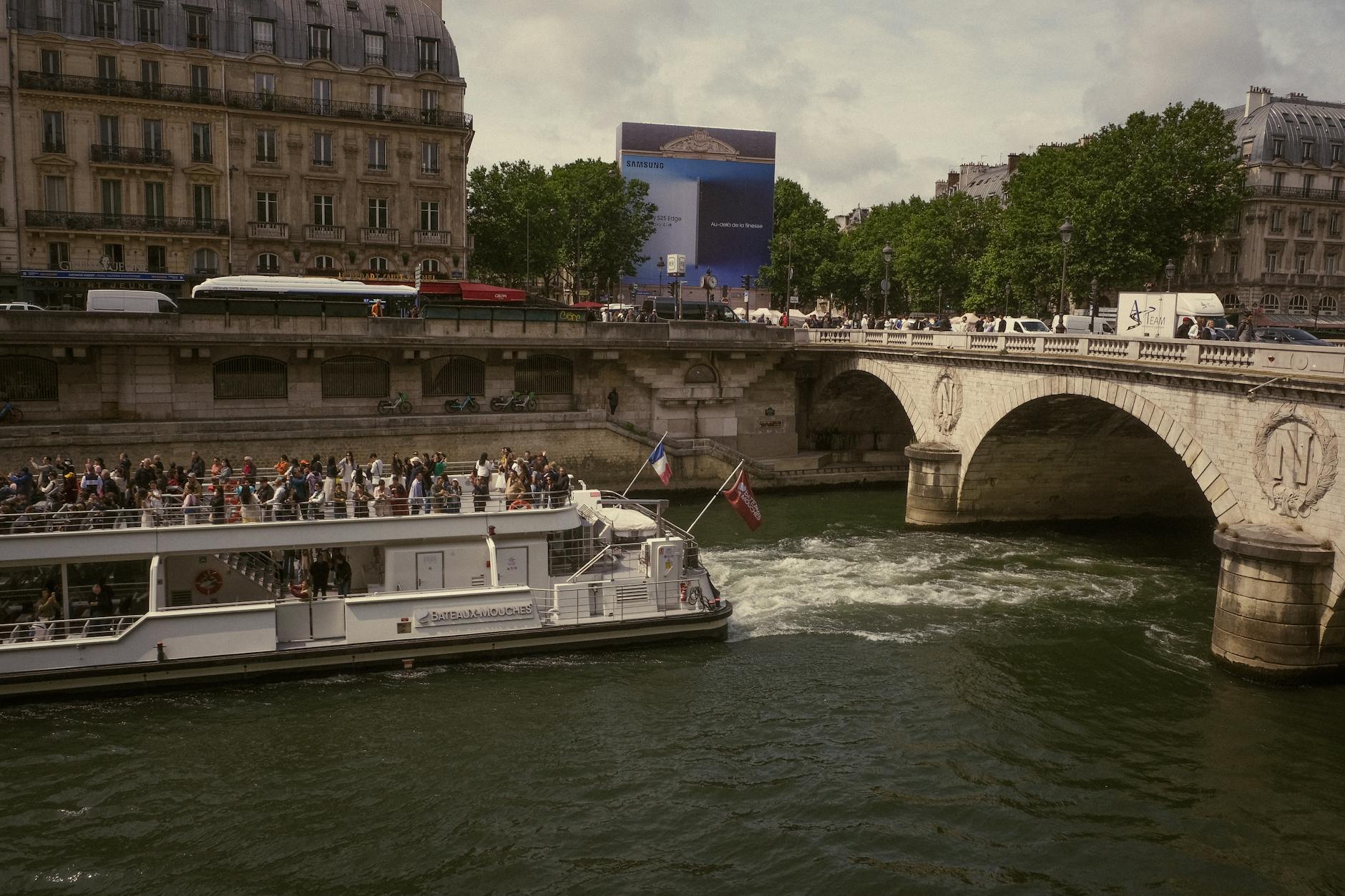 A cruise boat gliding along the Seine past classic Parisian buildings