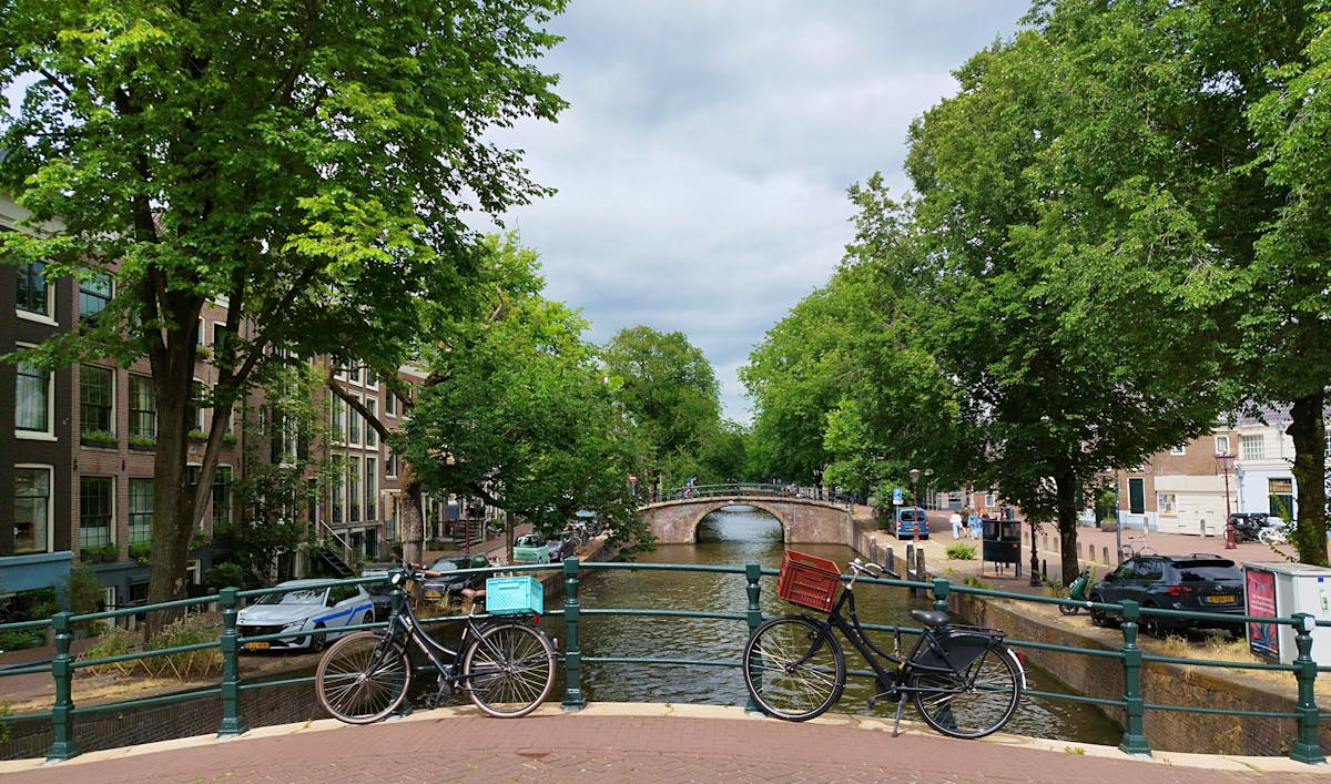 Stone bridge spanning an Amsterdam canal with traditional Dutch buildings behind
