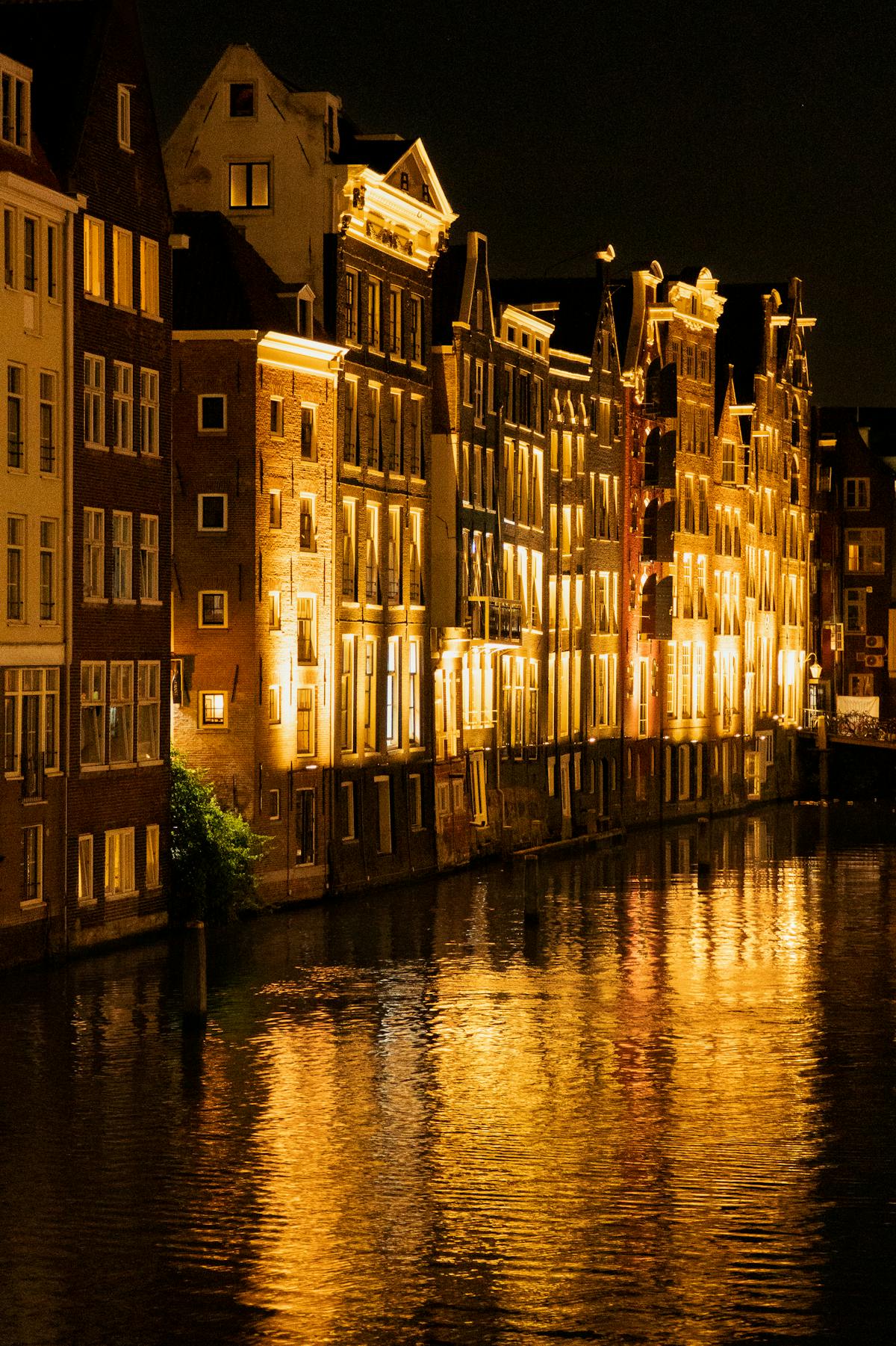 Amsterdam canal at night with lights reflecting on the water