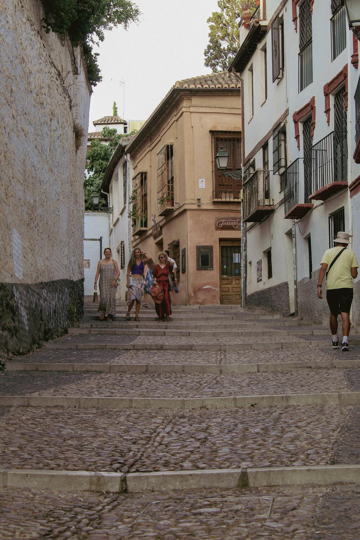 Cobblestone street in Granada old town with travelers walking past traditional architecture