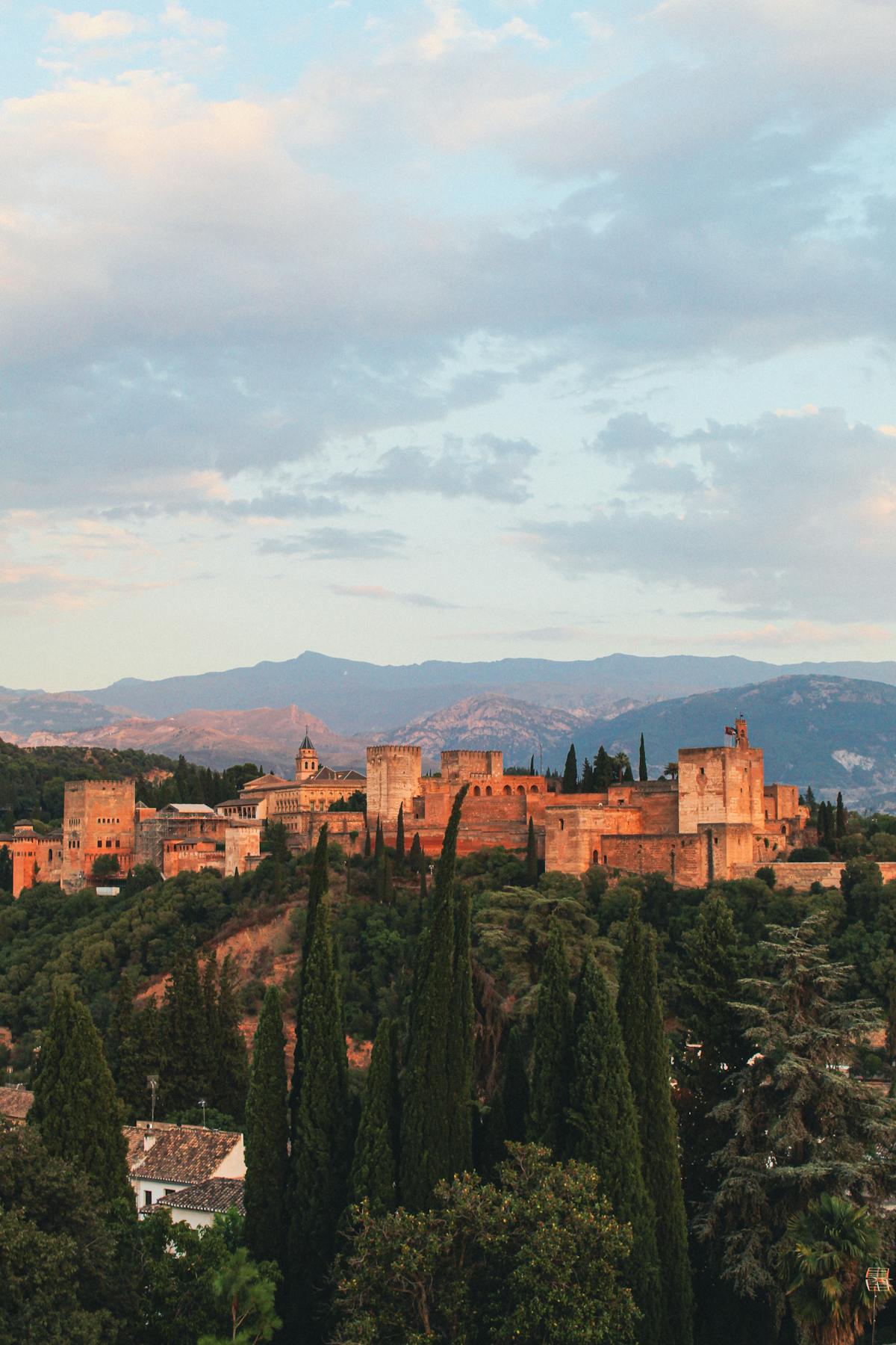 Sunset view of the Alhambra palace surrounded by lush greenery in Granada Spain
