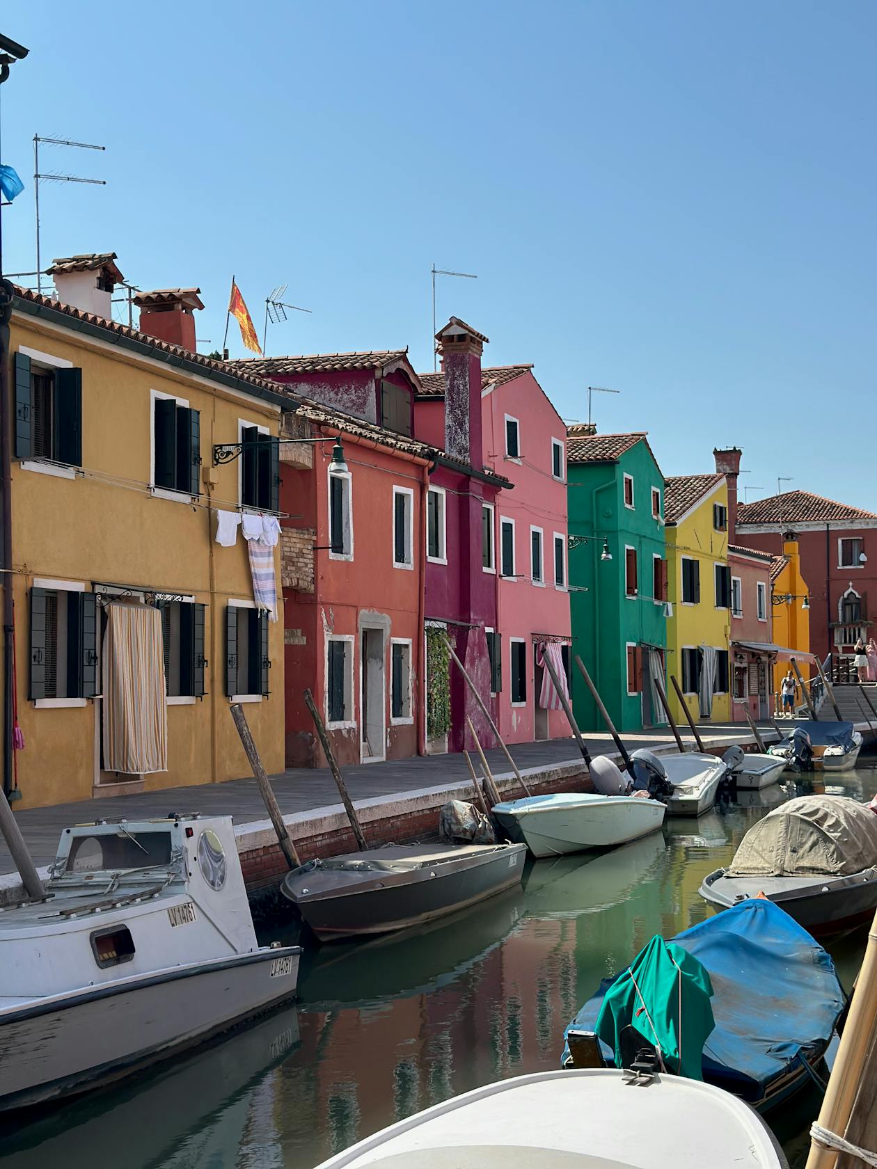 Colorful canal houses reflected in water in Burano Italy