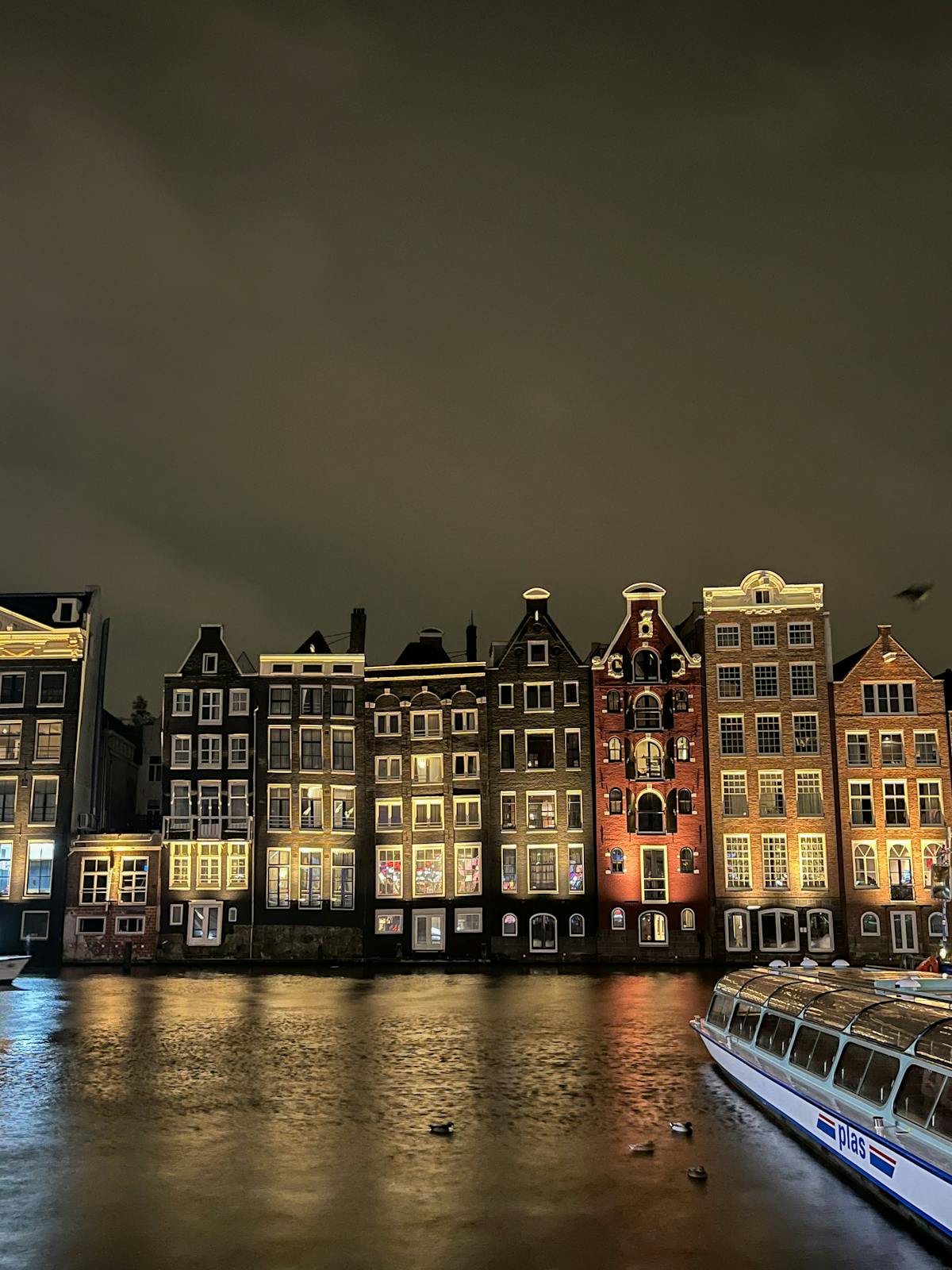 Amsterdam canal at dusk with golden light reflecting off the water and buildings