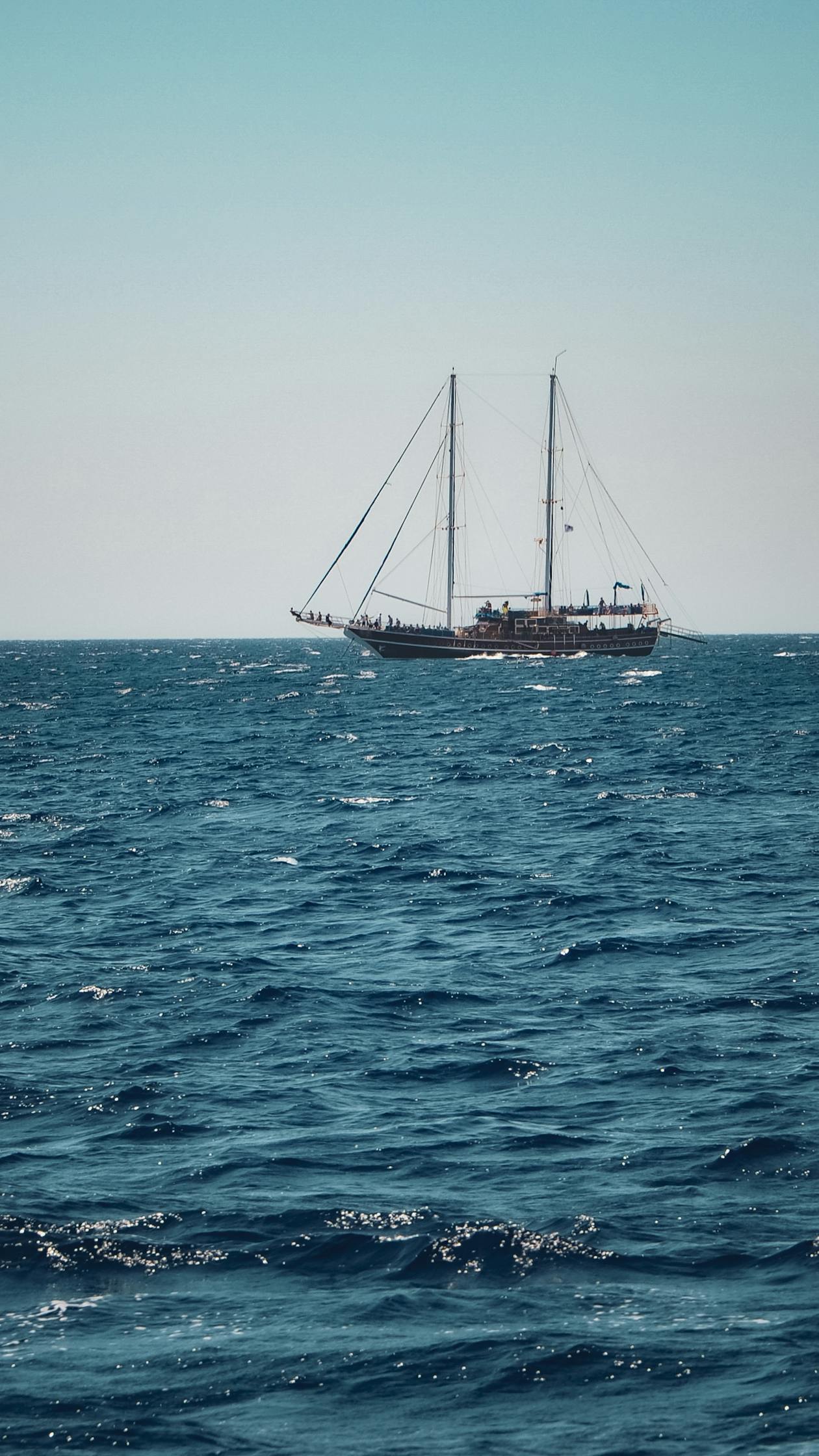 Large sailboat cutting through open sea with sails full of wind