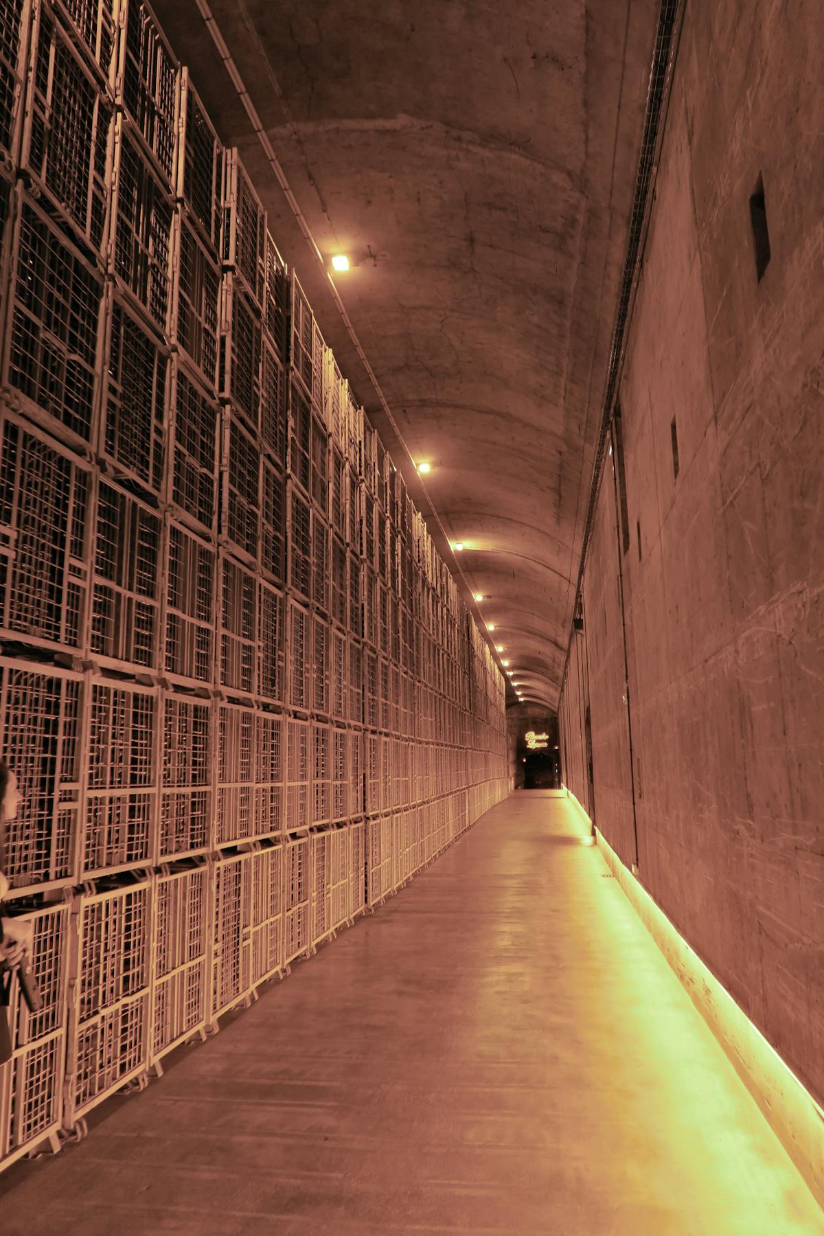 A dimly lit chalk tunnel in a Champagne house cellar with bottles stored on riddling racks
