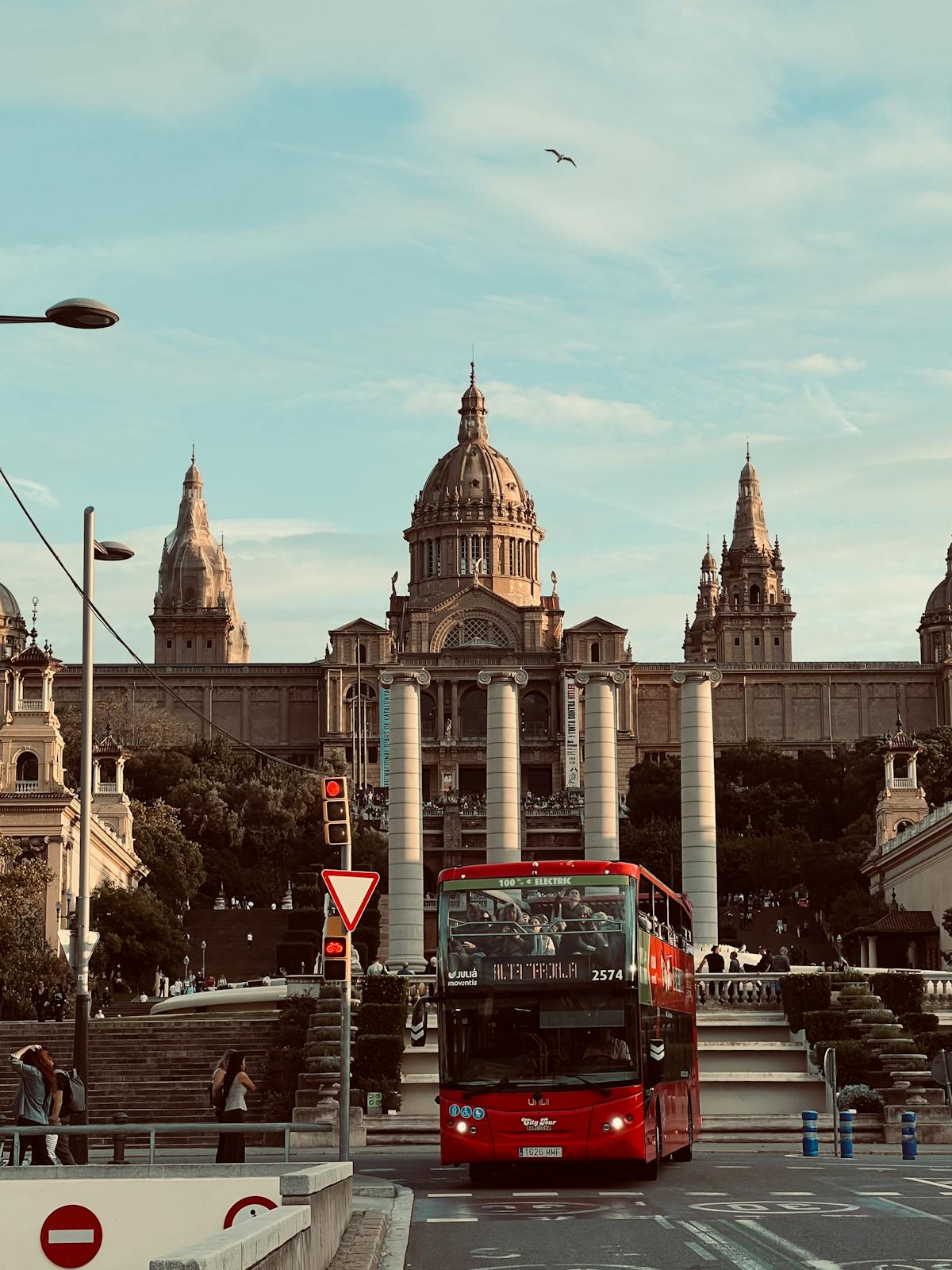 Red hop-on hop-off tour bus passing the National Art Museum of Catalonia in Barcelona with fountains in the foreground