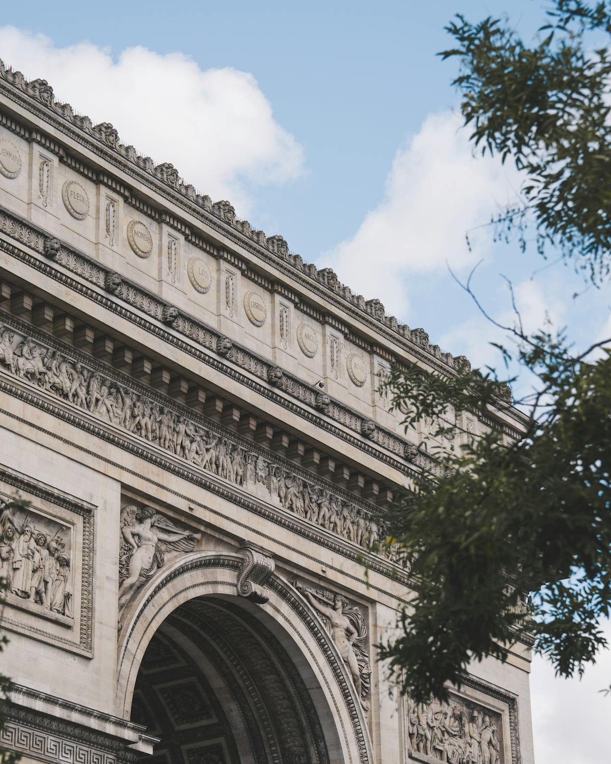 Detailed view of the Arc de Triomphe facade against a bright blue sky