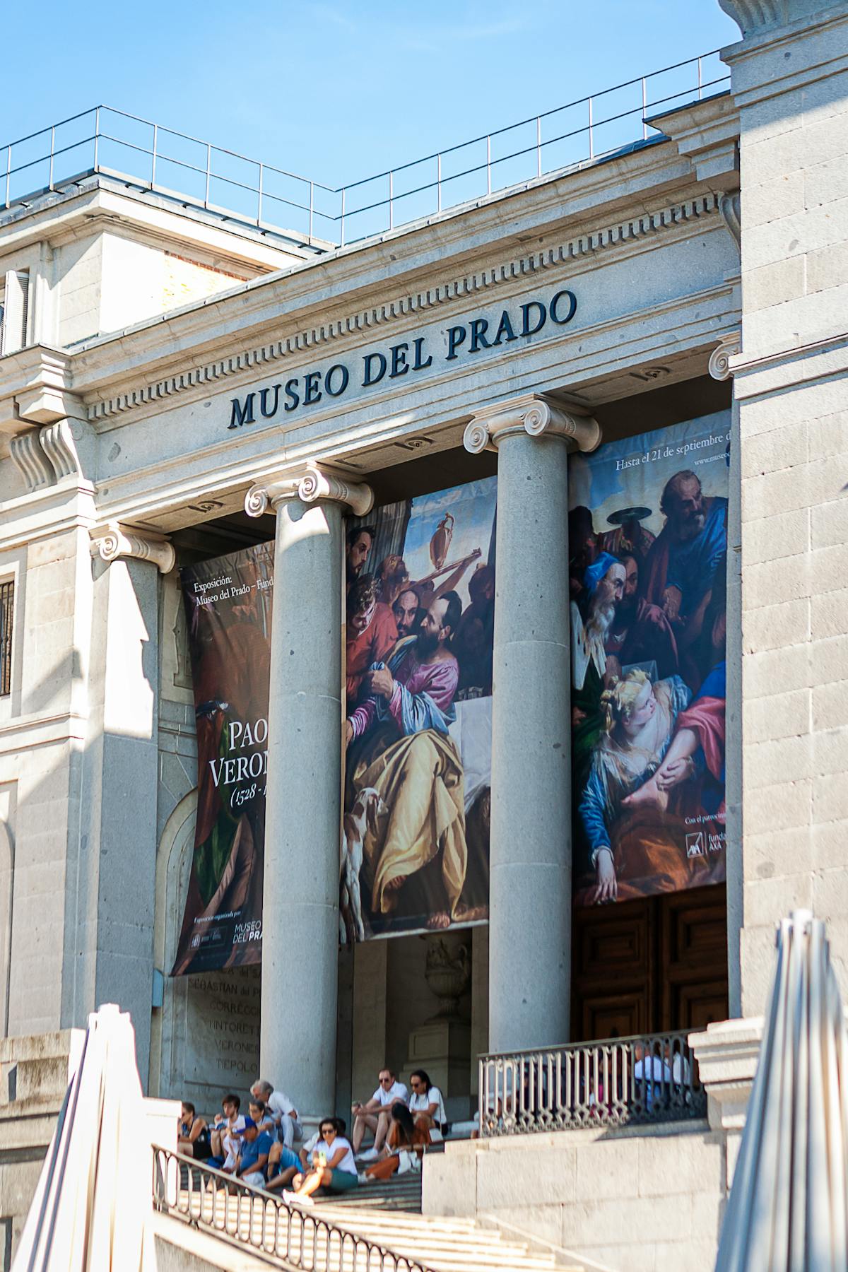 Front view of the Museo del Prado in Madrid with visitors walking outside on a bright day