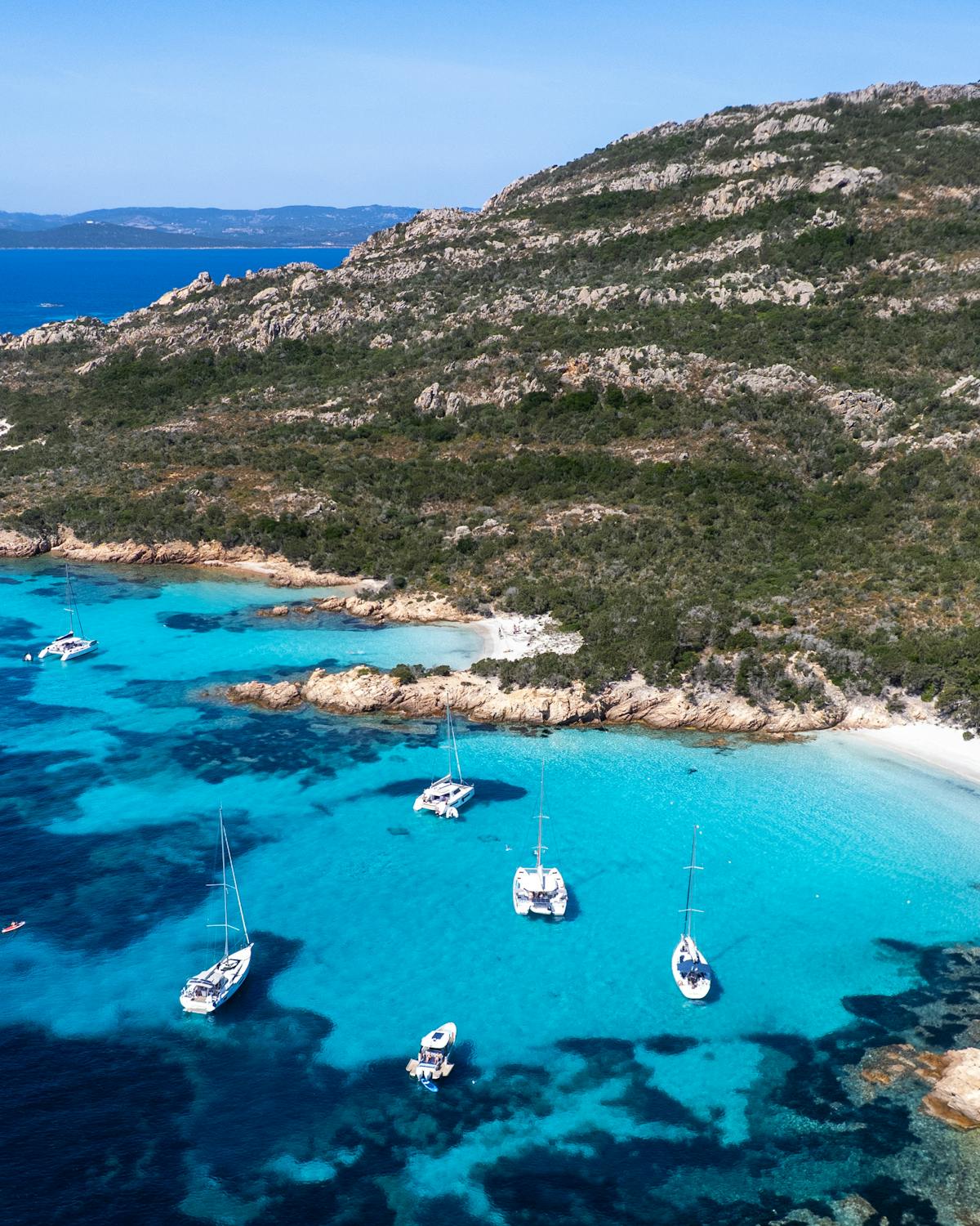 Aerial view of boats in clear azure waters in a Mediterranean bay