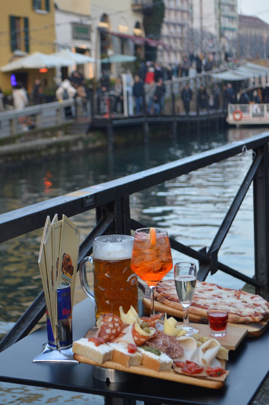 Classic Italian aperitivo with Aperol Spritz and snacks by a canal in Milan