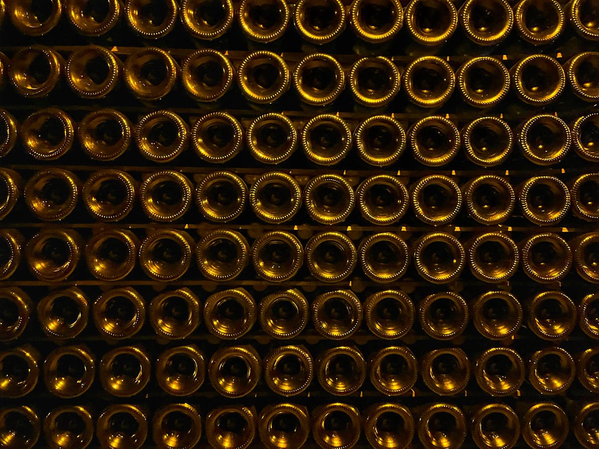 Stacked champagne bottles ageing in a dimly lit underground cellar with chalk walls