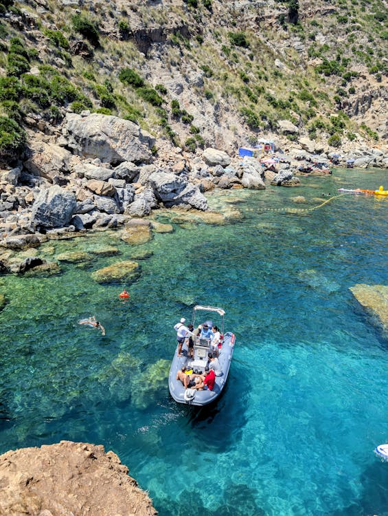 Mediterranean cove with swimmers and a boat in crystal clear waters