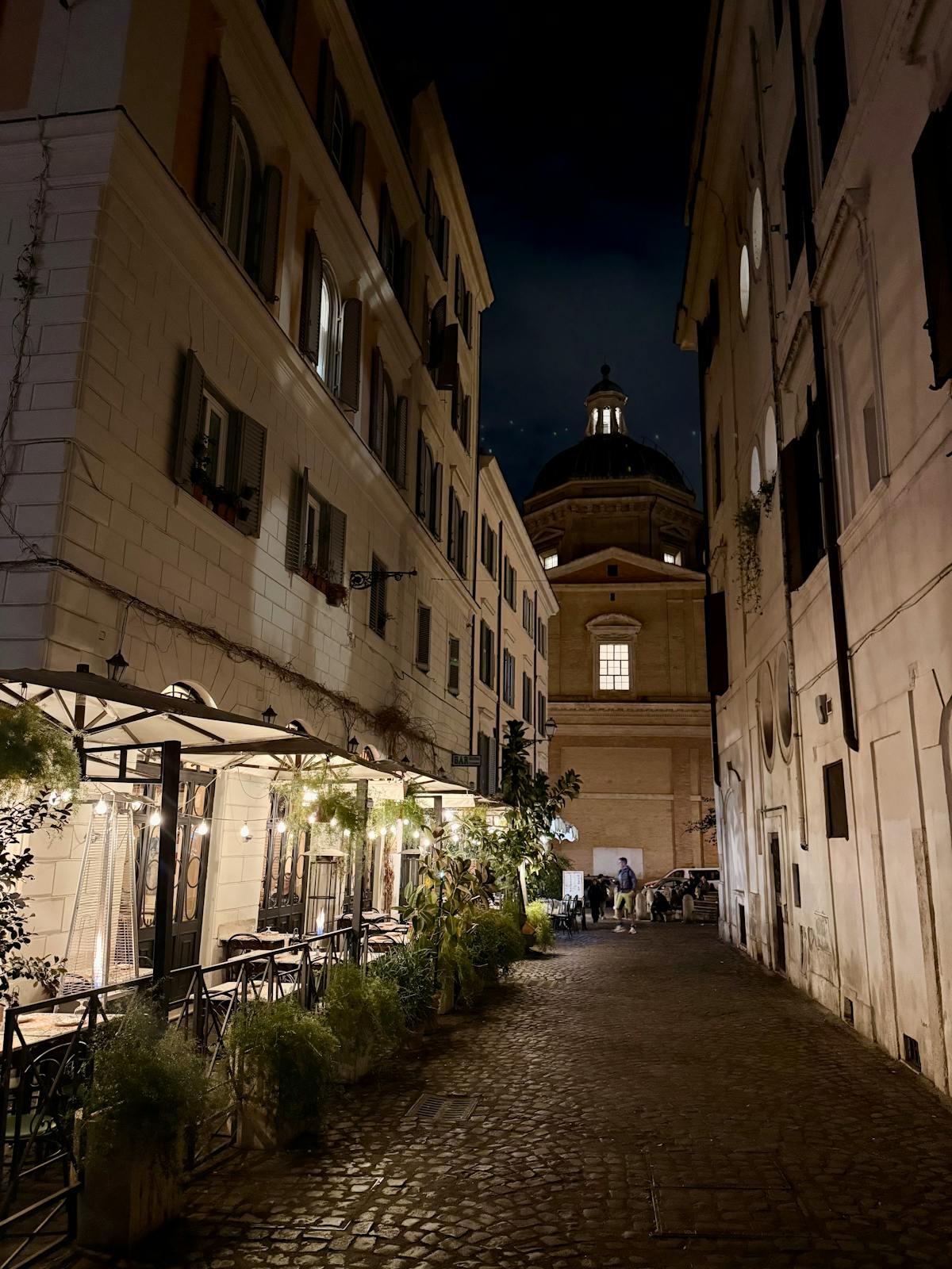 A quaint Roman alleyway at night with warm lighting