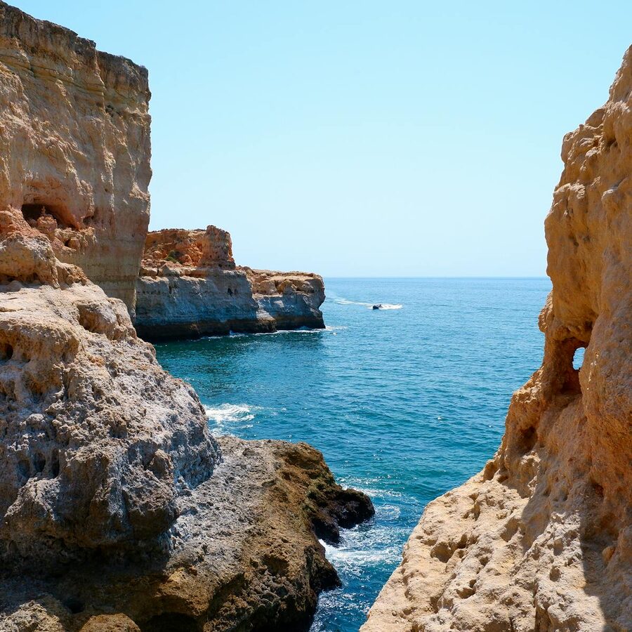 Dramatic limestone cliffs along the Algarve coastline with clear blue sky and ocean