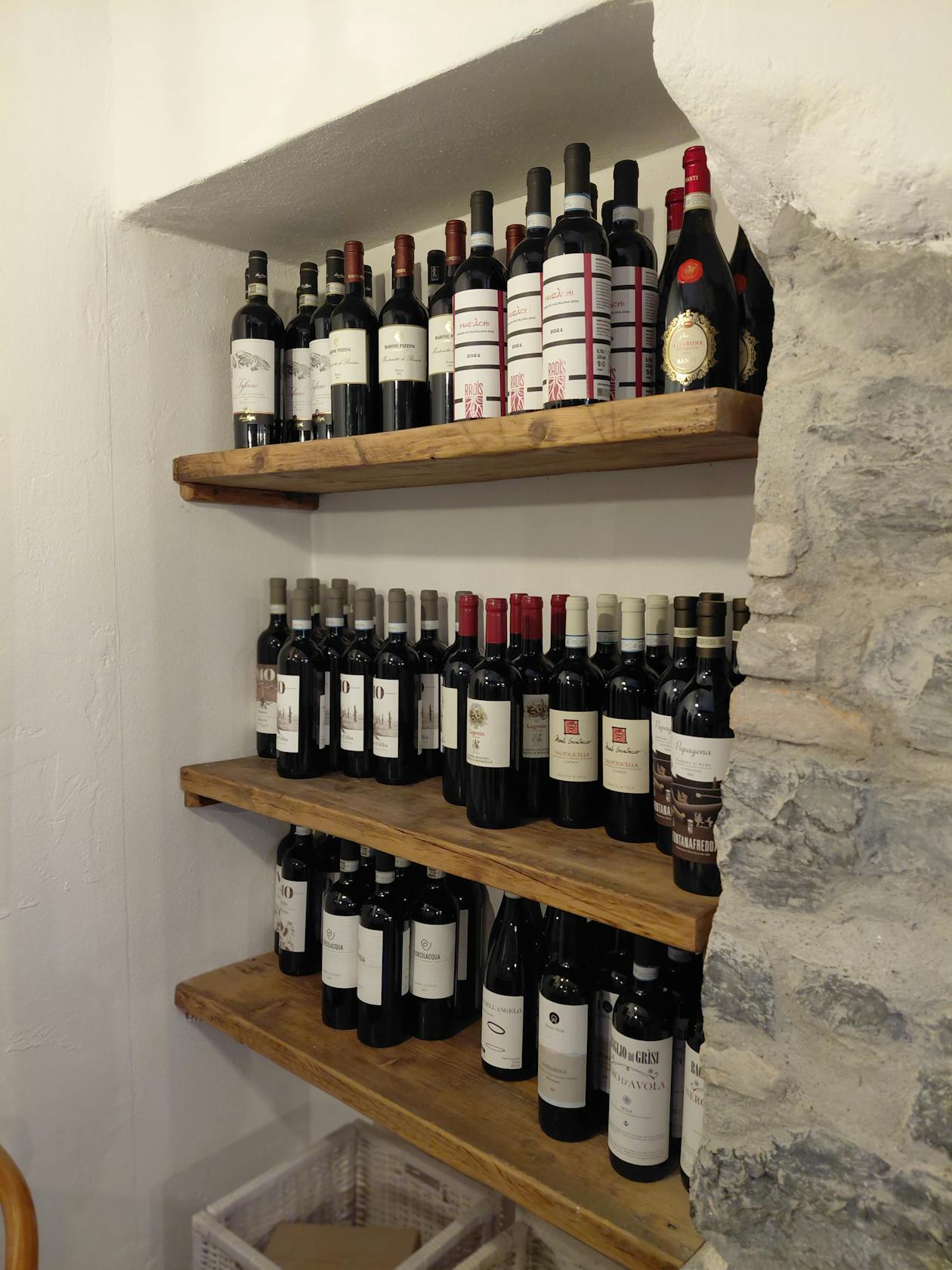 Shelves lined with wine bottles inside a traditional stone wine cellar