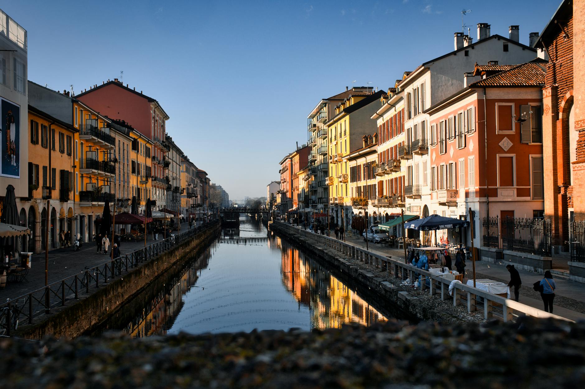 Outdoor cafes and colorful buildings lining a canal in the Navigli District of Milan