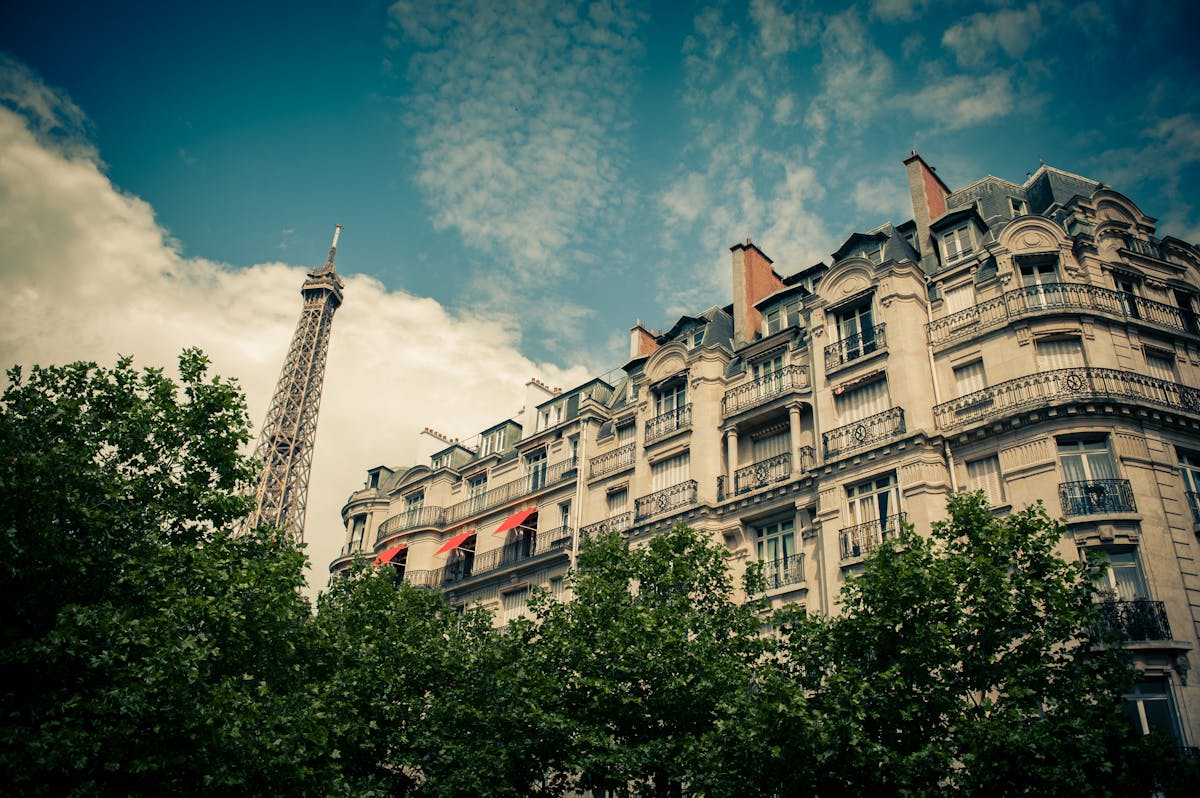 The Eiffel Tower glimpsed between classic Haussmann buildings on a Paris street