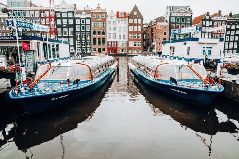 Traditional Amsterdam canal houses reflected in calm water with moored boats