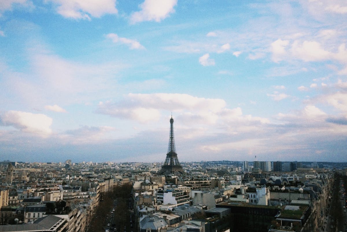Aerial panorama of Paris showing the Seine, rooftops, and tree-lined boulevards on a clear day