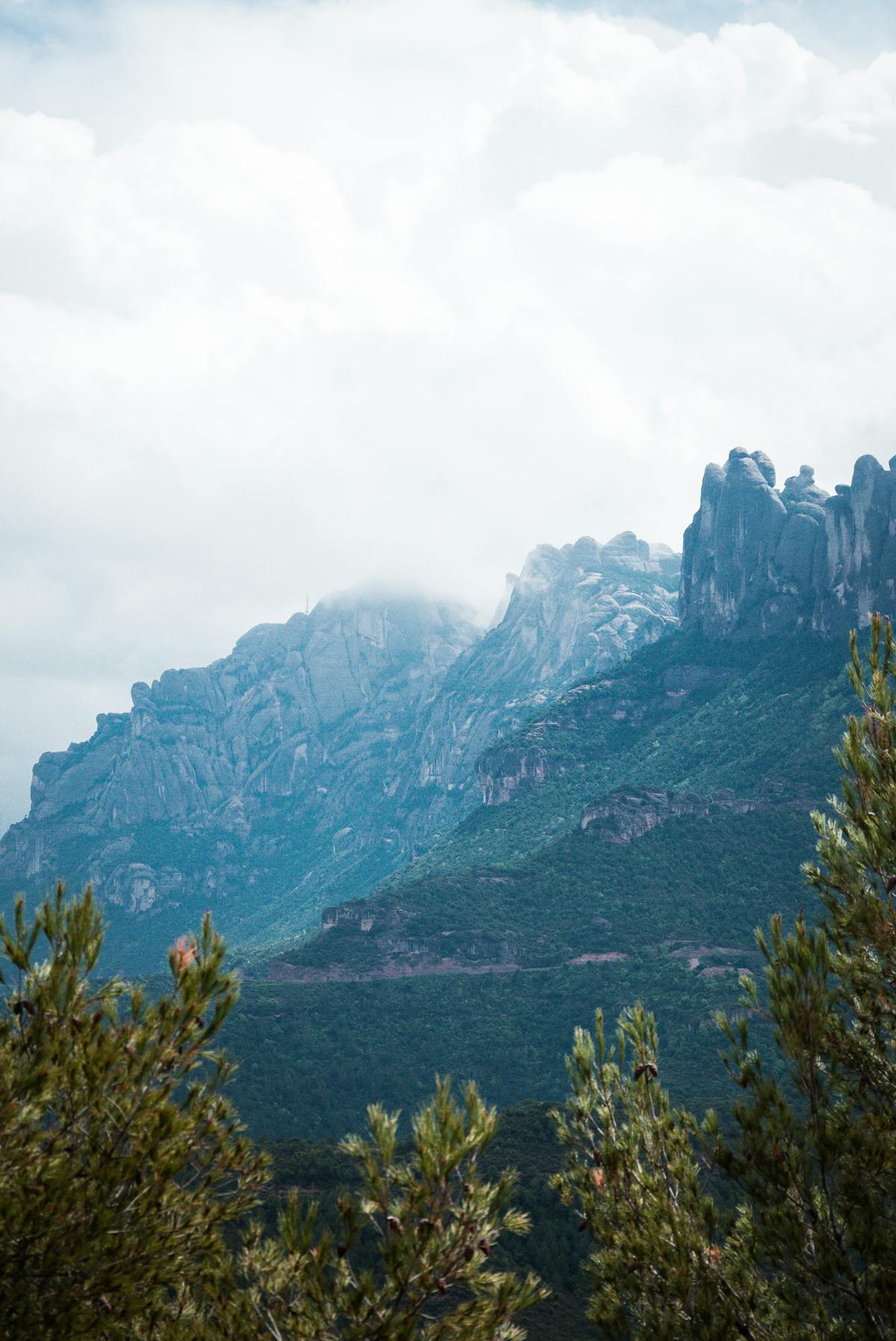 Visitors walking along a stone path toward Montserrat monastery with peaks towering above
