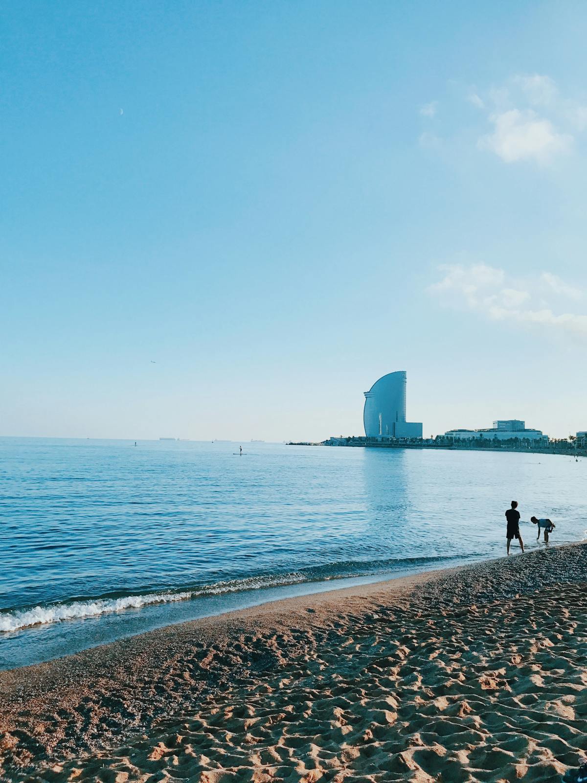 Sunny beach scene at Barcelona seafront with the W Hotel visible in the distance